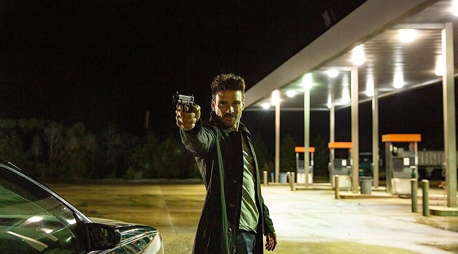 Sloan, gespielt von Frank Grillo, steht mit gezückter Pistole an einer Tankstelle.
