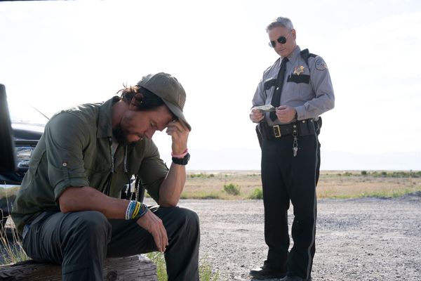 Joe Bell, gespielt von Mark Wahlberg, sitzt am Straßenrand, Sheriff Westin, gespielt von Gary Sinise, bietet ihm Hilfe an.