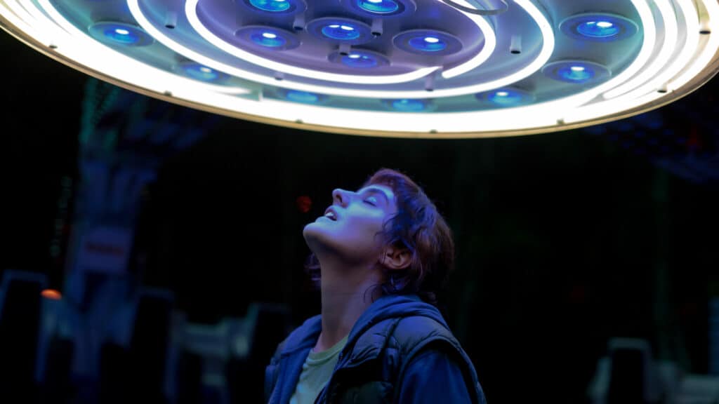Jeanne (Noémie Merlant) spurt die Energie von JUMBO, der Freizeitparkattraktion, deren Lichter über ihrem Kopf leuchten.
