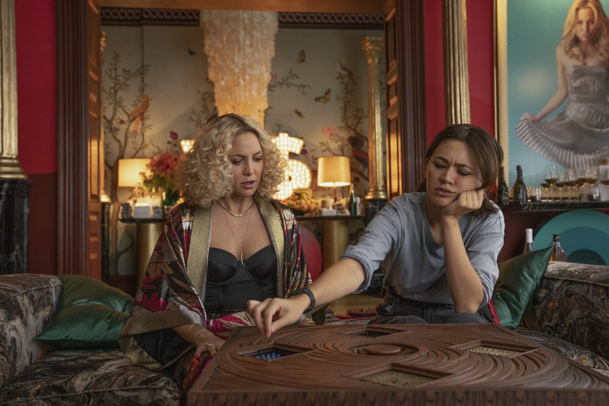 Kate Hudson und Jessica Henwick mit einem Holzspielbrett beschäftigt in einem eleganten Salon. Glass Onion