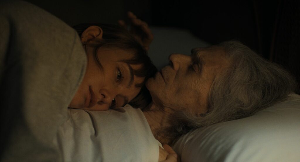 Die Großmutter Pilar liegt schlafend auf dem Rücken, ihre Enkelin liegt mit ihrem Kopf auf Pilars Brust in La Abuela