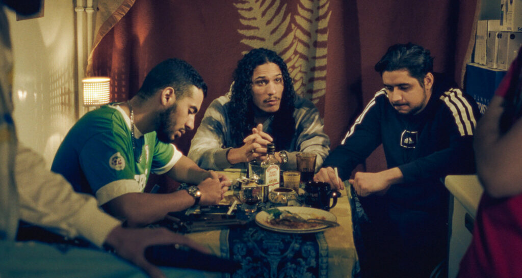 Im Film Lockdown Tower sitzt Hatik als Ahmed mit seinen Kumpels am Tisch und schmiedet Plände.