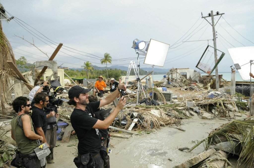Kameramann und sein Team bei den Dreharbeiten, um sie herum eine verwüstete Siedlung