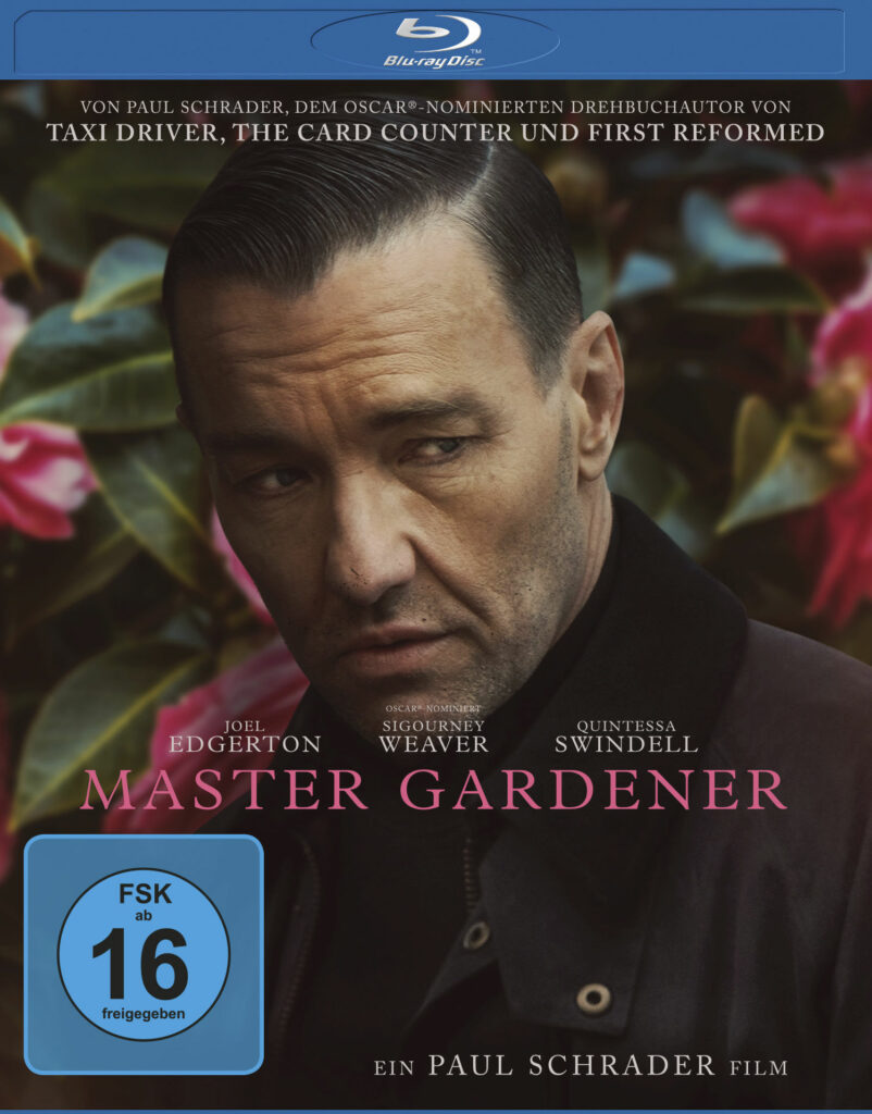 Auf dem Blu-ray-Cover des Films Master Gardener sind im Bildhintergrund Blumensträucher mit rötlichen Blüten zu sehen. Im Vordergrund ist ein Mann mit schwarzen Haaren und Undercut-Frisur zu sehen. Er trägt eine dunkle Jacke. Es ist der Schauspieler Joel Edgerton.