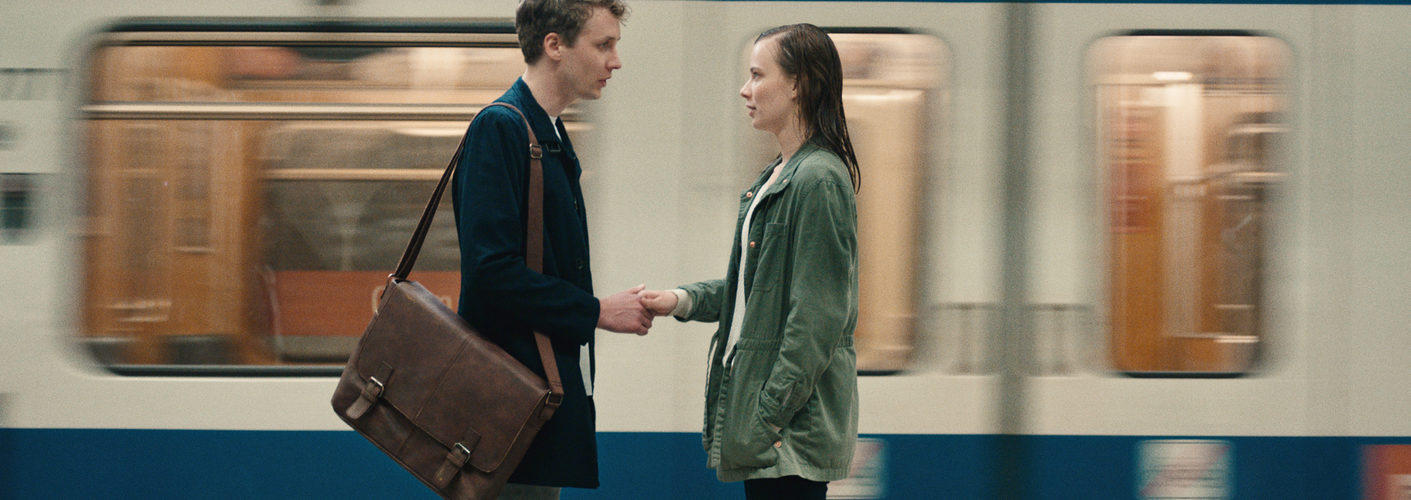 Aron, gespielt von Julius Feldmeier, und Nora, gespielt von Saskia Rosendahl, stehen sich in der U-Bahnstation gegenüber und lernen sich kennen.
