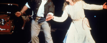 Dan Aykroyd und Kim Basinger halten sich die Hände und scheinen zu tanzen und zu singen. - "Meine Stiefmutter ist ein Alien"