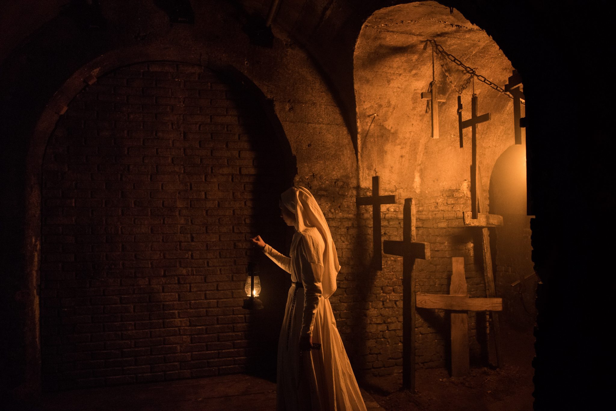 Eine Nonne schleicht durch Katakomben, die Petroleumlampe in der Hand, hinter ihr hängen Kreuze