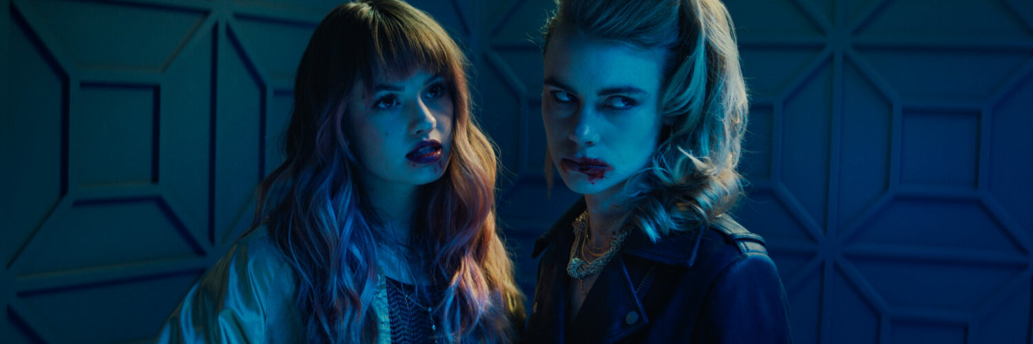 Blaire und Zoe mit lasziven Gesichtsausdruck spärlich beleuchtet in einem dunklen Raum in Night Teeth.