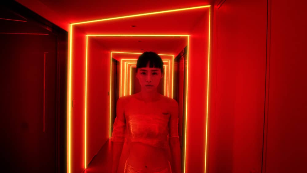 Wegen einer Schönheitskur lediglich von etwas Plastikfolie an den prekären Stellen bedeckt, schreitet Nina Wu (Wu Ke-Xi) durch einen von Neonleuchten komplett in rot gefärbten Gang.
