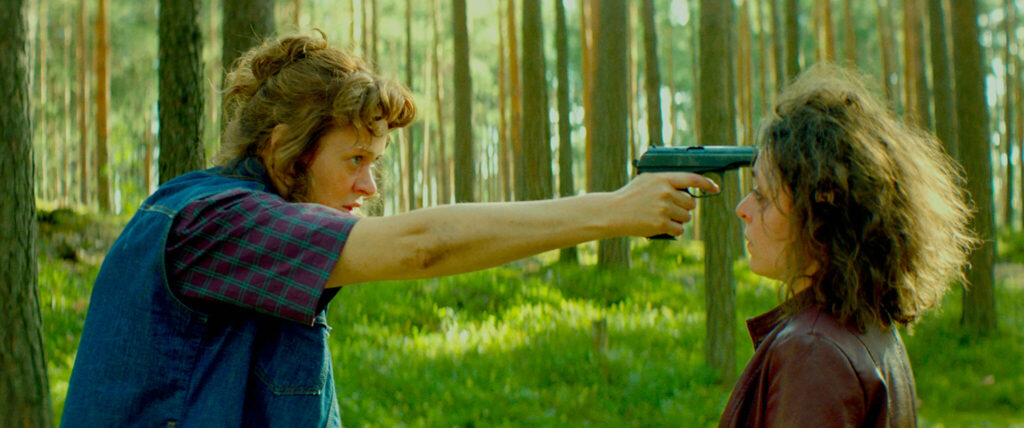 Anna Mikhalkova als Vera hält im Film No Looking Back mitten im Wald ihrer Filmtochter Olga, gespielt von Viktoriya Korotkova, eine Pistole an die Stirn.