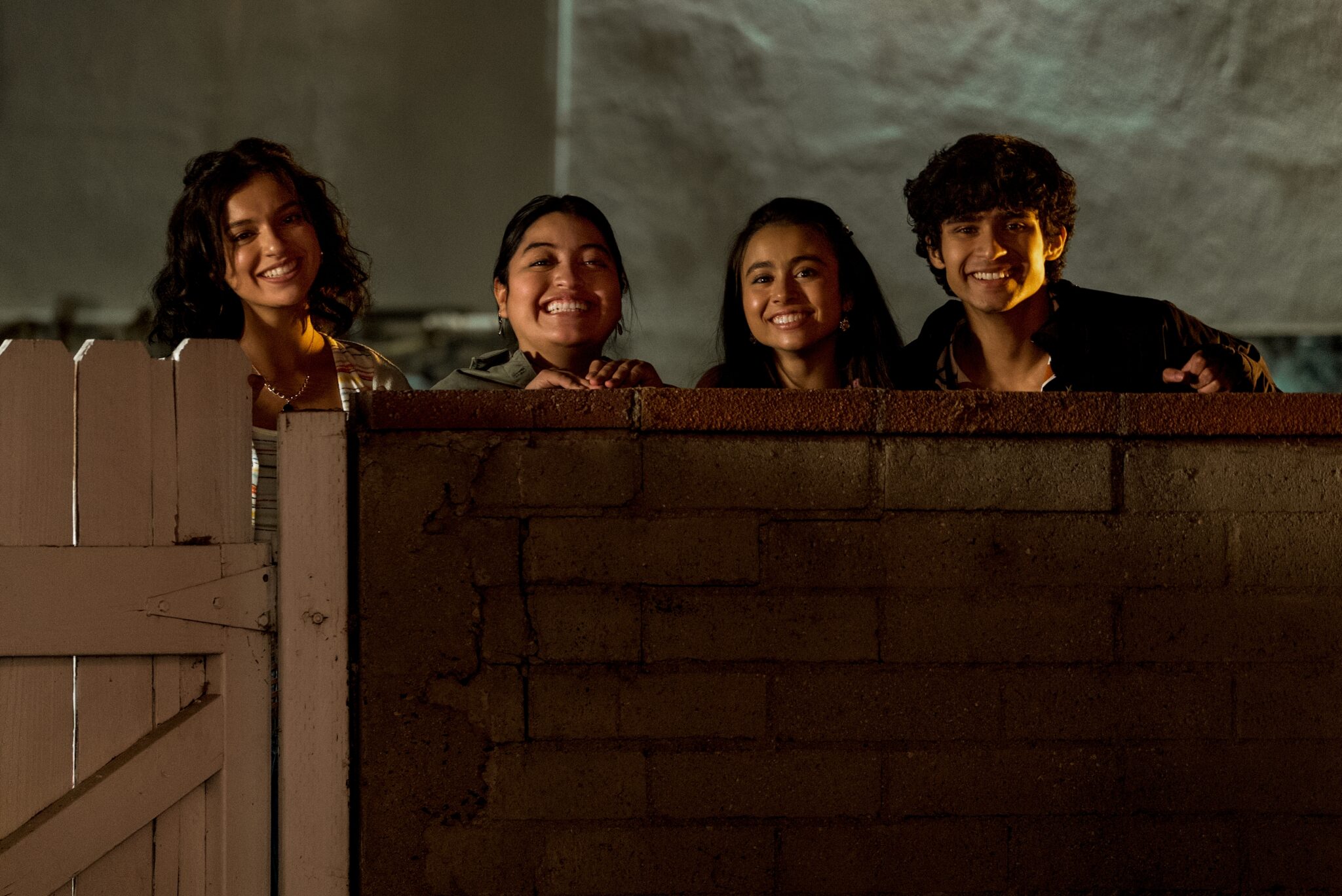 Vier Lateinamerikanische Jugendliche, die über eine Mauer schauen und alle grinsen. Coming of Age-Serien Tipps