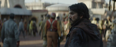 Diego Luna als Cassian Andor auf einem belebten Platz im Vordergrund. Die Personen hinten im Bild sind unscharf.