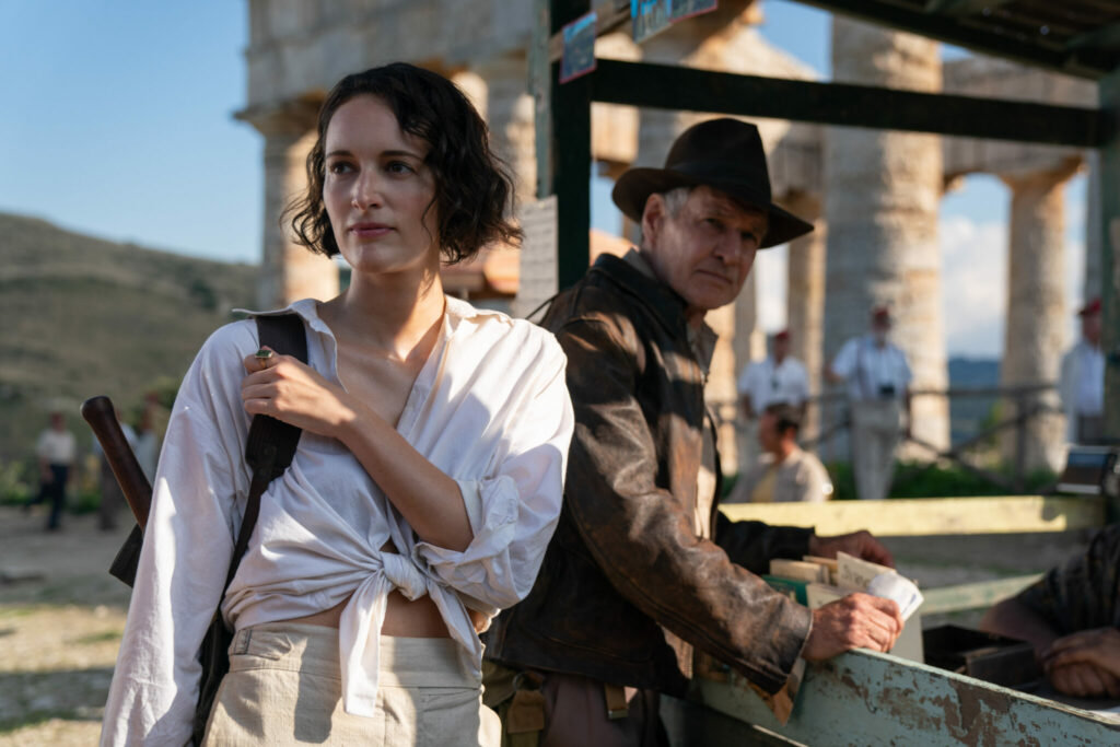 Eine Frau in weißer Bluse und halblangen Haaren steht links neben einem Mann mit Hut und Lederjacke. Links steht die Schauspielerin Phoebe Waller-Bridge und rechts Harrison Ford. Eine Szene aus Indiana Jones und das Rad des Schicksals.