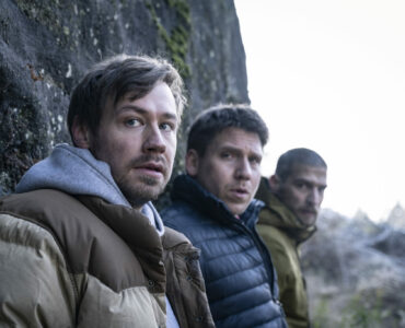 Man sieht die drei Teilnehmer des Junggesellenabschieds Roman, Albert und Peter nebeneinander an einer Felswand stehend.