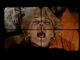 Eine Kamera mit visuellem Fadenkreuz ist auf eine schreiende Frau mit blonder Kurzhaarfrisur gerichtet