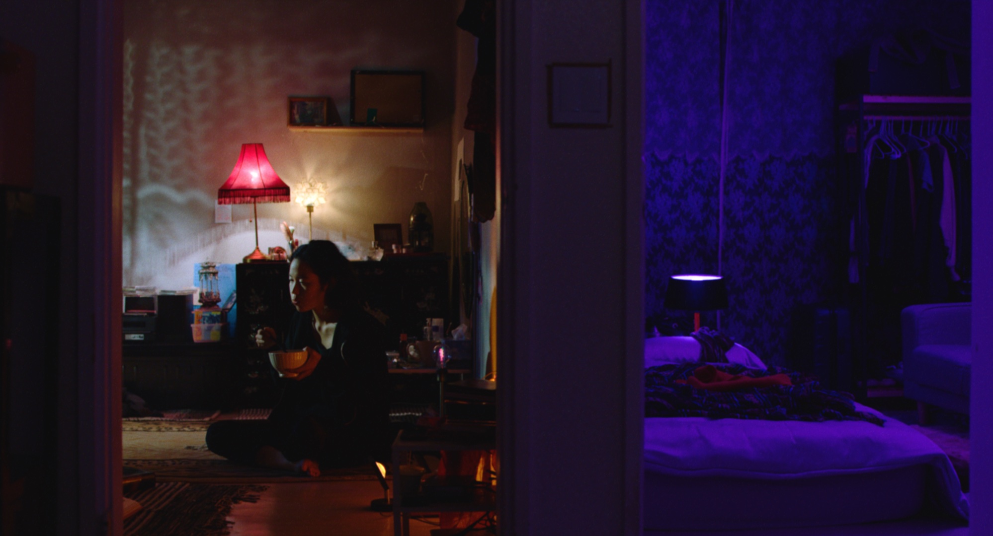 Die Protagonistin von Return to Seoul in einem dunklen Zimmer auf dem Boden sitzend beim Essen.