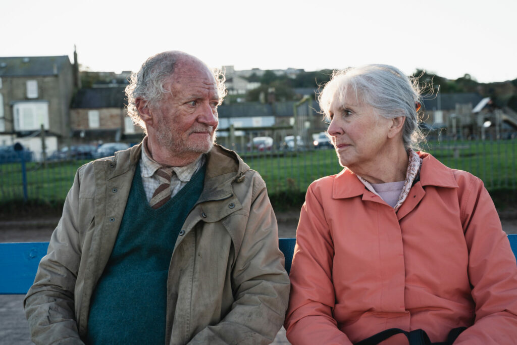Harold, gespielt von Jim Broadbent, und seine Frau Maureen, gespielt von Penelope Wilton, sitzen zusammen auf einer Bank, erstes Zeichen einer erneuten Annäherung.