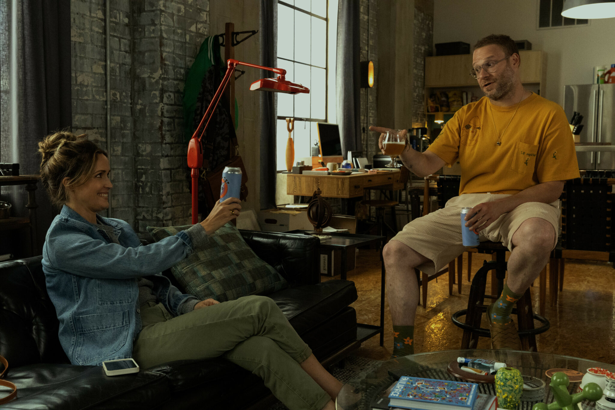Rose Byrne und Seth Rogen in Platonic in einem Wohnraum sitzend. Beide halten Bierdosen in den Händen.