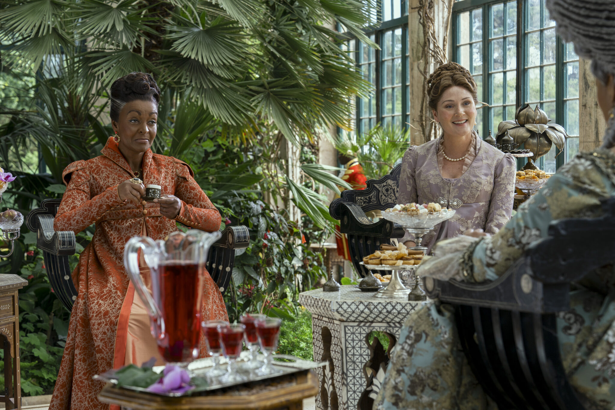 Adjoa Andoh als Lady Agatha Danbury, Ruth Gemmell als Lady Violet Bridgerton in einem Wintergarten beim Tee.