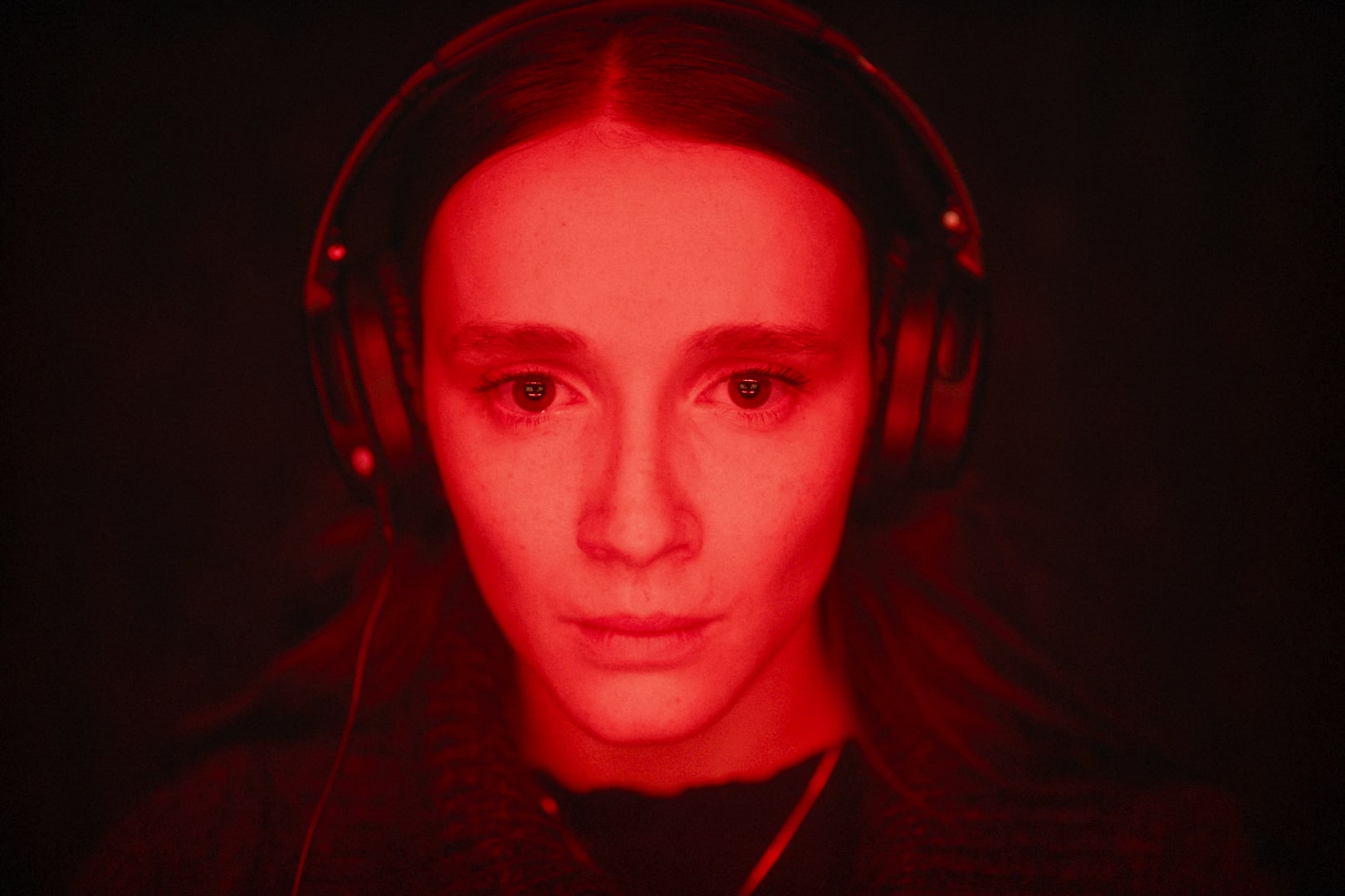 Eine junge Frau im Rotlicht im Porträt mit Kopfhörern