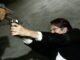 Ein Mann im schwarzen Anzug hält eine Waffe im Liegen und richtet sie auf ein unbekanntes Ziel. Eine Szene aus dem Film Reservoir Dogs.