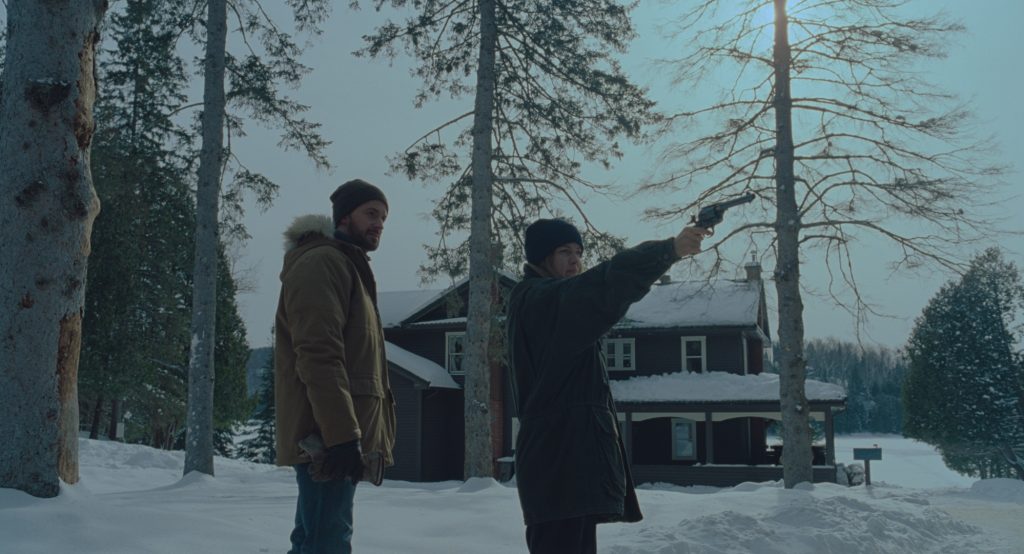 Richard (Richard Armitage) zeigt seiner Verlobten im schneebedeckten Wald, wie man mit einer Waffe umgeht in The Lodge © 2019 SquareOne Entertainment