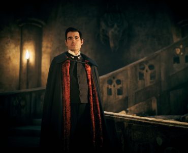 Dracula steht in einer dunklen und roten Robe in einem alten Gemäuer