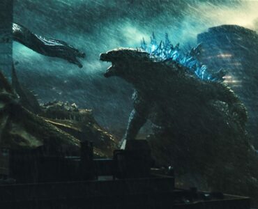Das Bild zeigt eine Szene aus dem Film "Godzilla 2: King of the Monsters", wo sich die titelgebende Riesenechse Godzilla und der dreiköpfige Drache Ghidorah zu sehen, die sich vor einem malerischen Hintergrund anfauchen - Streamcatcher Podcast Februar 2021.