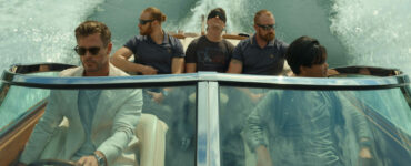 Fünf Männer in einem Speedboat, einer in der Mitte mit verbundenen Augen.