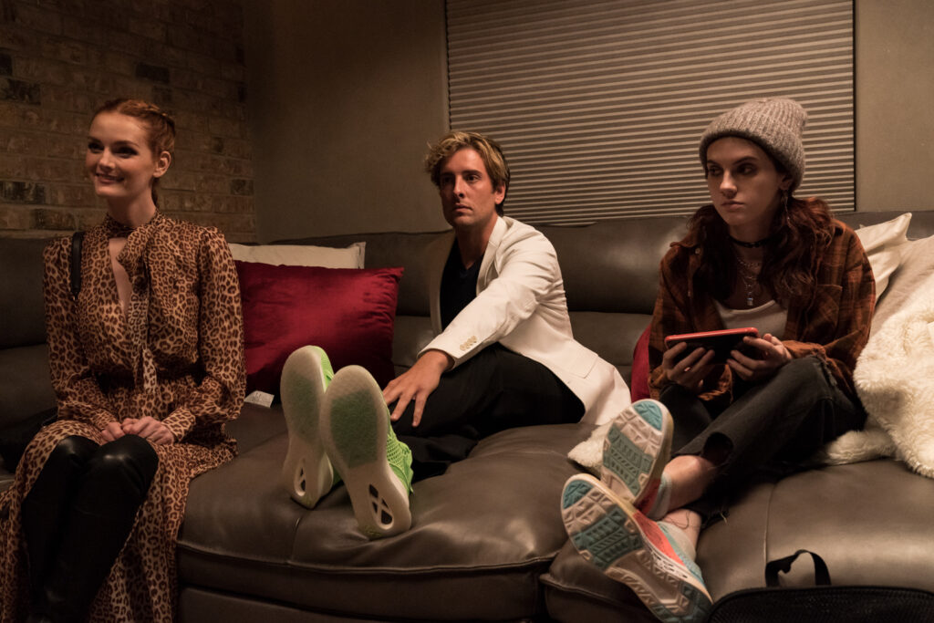 Lydia Hearst, Jack Donnelly und Sara Hayward sitzen auf einer großen, grauen Couch - Slayers