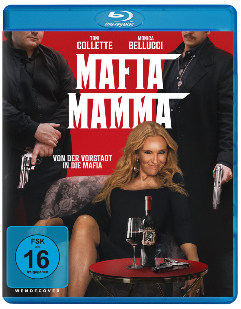 Toni Collete in Schwarz als Mafia Bossin auf einem Stuhl, flankiert von zwei Bodyguards
