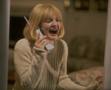 Eine Frau mit blonden Haaren schreit mit einem Telefon in der Hand