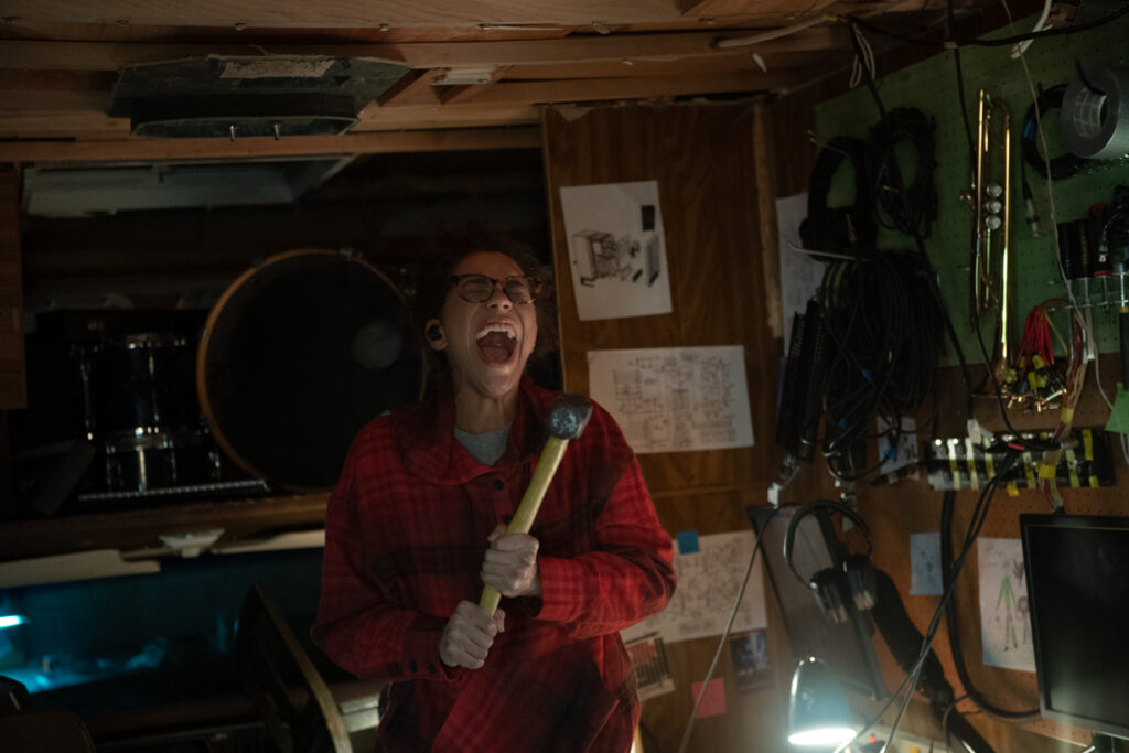 Jasmin Savoy Brown als Alexis in Sound of Violence steht schreiend mit einem Hammer in der Hand in einem Wohnwagen