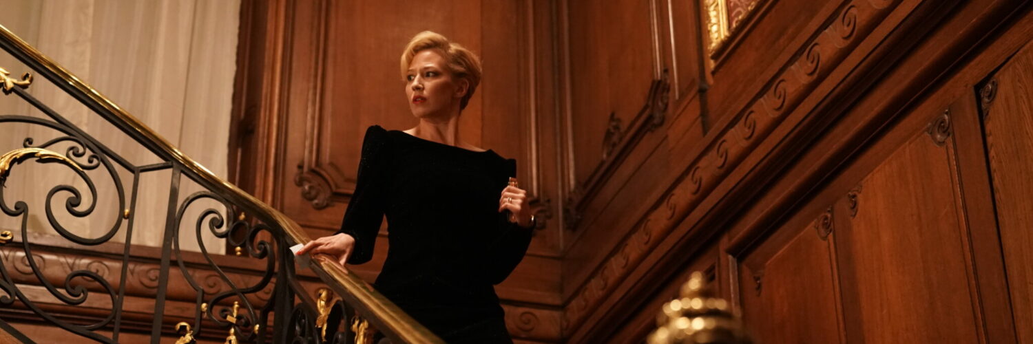 Allison O'Hara (Carrie Coon) in einem Treppenhaus. Sie trägt ein schwarzes Abendkleid.