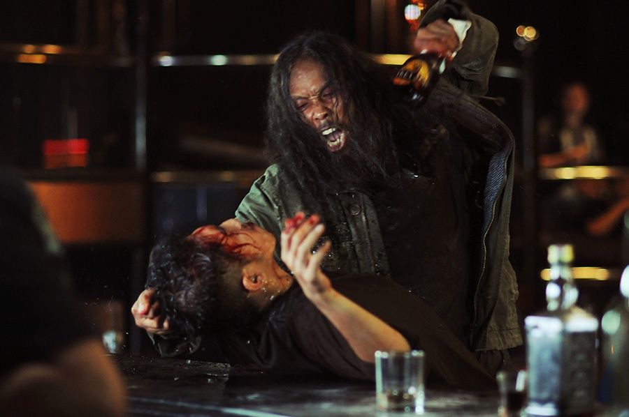 In The Raid 2 hält Yayan Ruhian als Prakoso seinem blutüberströmten Gegner eine abgebrochene Flasche an den Hals.
