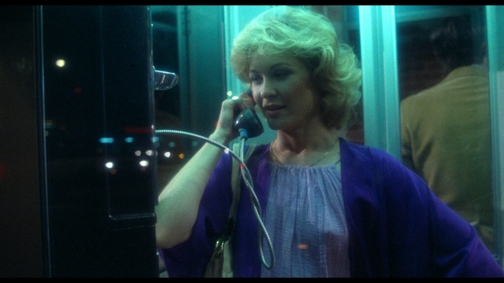 Darstellerin Dee Wallace steht in einer Telefonzelle mit dem Hörer in der Hand