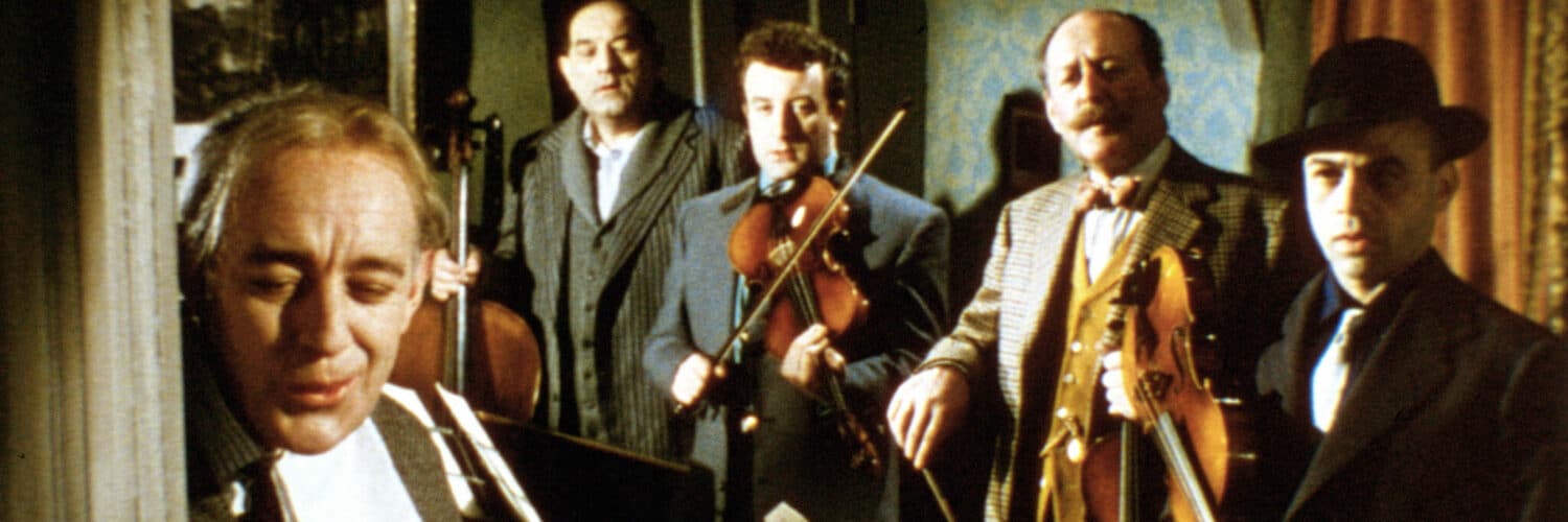 Die fünf Kriminellen um Professor Marcus (Alec Guinness) geben sich in Ladykillers gegenüber Mrs. Wilberforce (Katie Johnson) als Streicherquintett aus. Sie stehen stramm im gemieteten Zimmer und halten die Instrumente als Tarnung in der Hand.