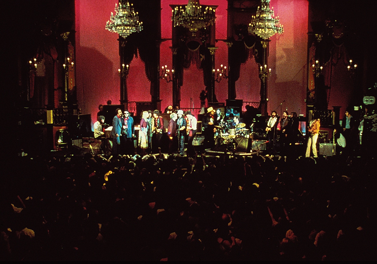 Die Mitglieder von The Band spielen zusammen mit allen Gaststars Bob Dylans "I shall be released". Über den Musikern sind drei Kronleuchter zu erkennen und im Vordergrund steht abgedunkelt das Publikum.