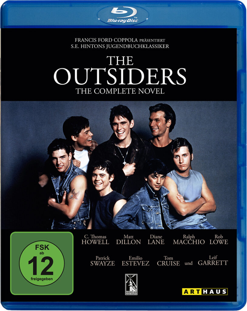 Auf dem Cover der Blu-ray von The Outsiders ist die im Film porträtierte Jugendbande The Greasers abgebildet, wie sie lachend und freundschaftlich vor einem neutralen Hintergrund posieren. Dabei tragen sie Lederjacken und Tanktops und wirken so, als ob sie für ein Gruppenbild vor neutralem Hintergrund fotografiert werden. © Studiocanal