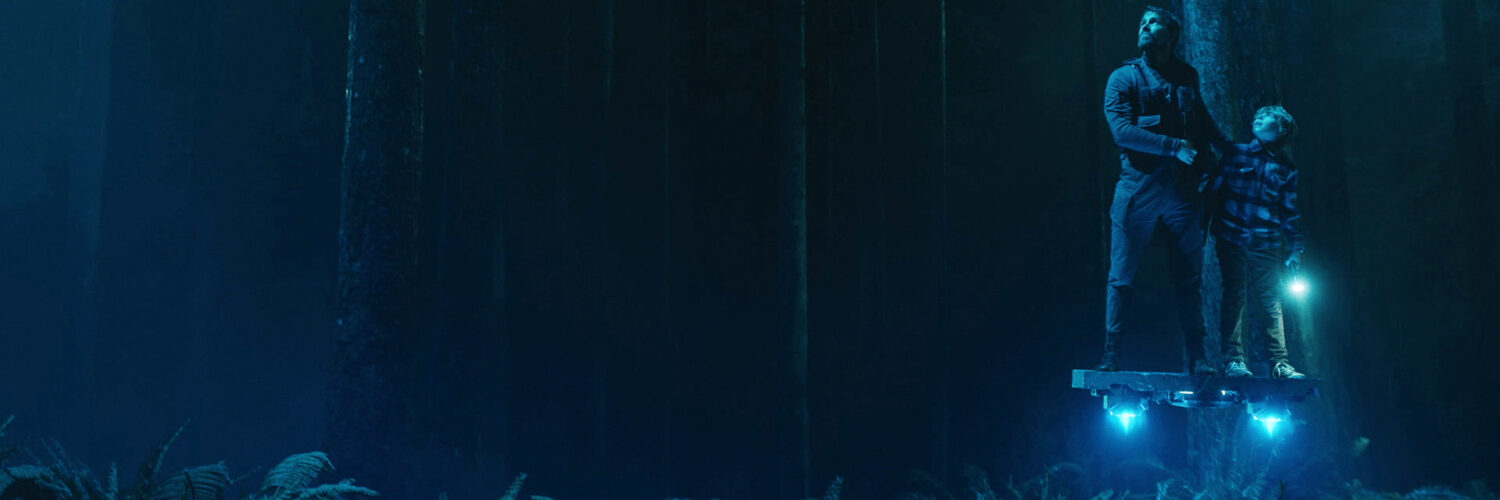 Zwei Personen schweben auf einem beleuchteten Brett im dunklen Wald