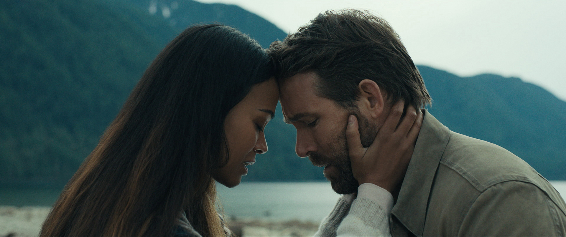 Zoe Saldana und Ryan Reynolds Stirn an Stirn mit geschlossenen Augen. Im Hintergrund ein See und Berge. The Adam Project