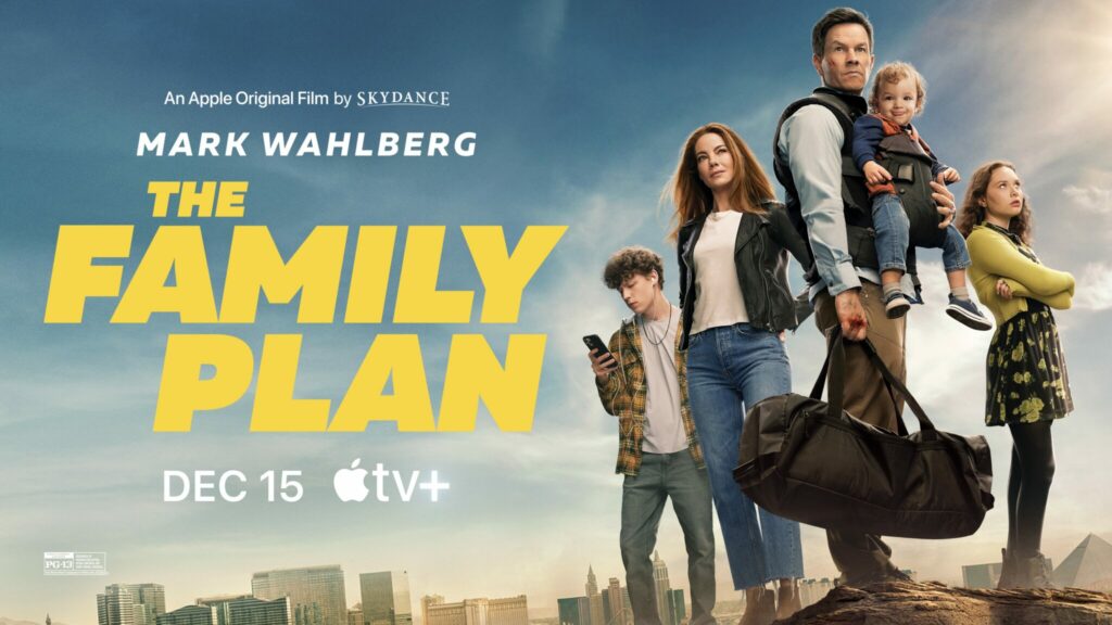 Auf dem Filmplakat zu " The Family Plan" ist die fünfköpfige Familie um Schauspieler Mark Wahlberg zu sehen. diese stehen nebeneinander, Wahlberg schaut mit strengen Blick und hat das Baby der Familie vor seinem Brustkorb geschnallt, während die restlichen drei seitlich neben ihm platziert stehen.