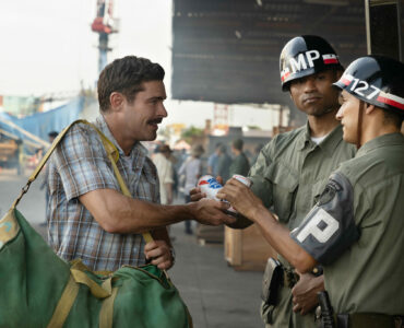 Chickie Donohue verteilt zwei Dosen Bier an amerikanische Soldaten