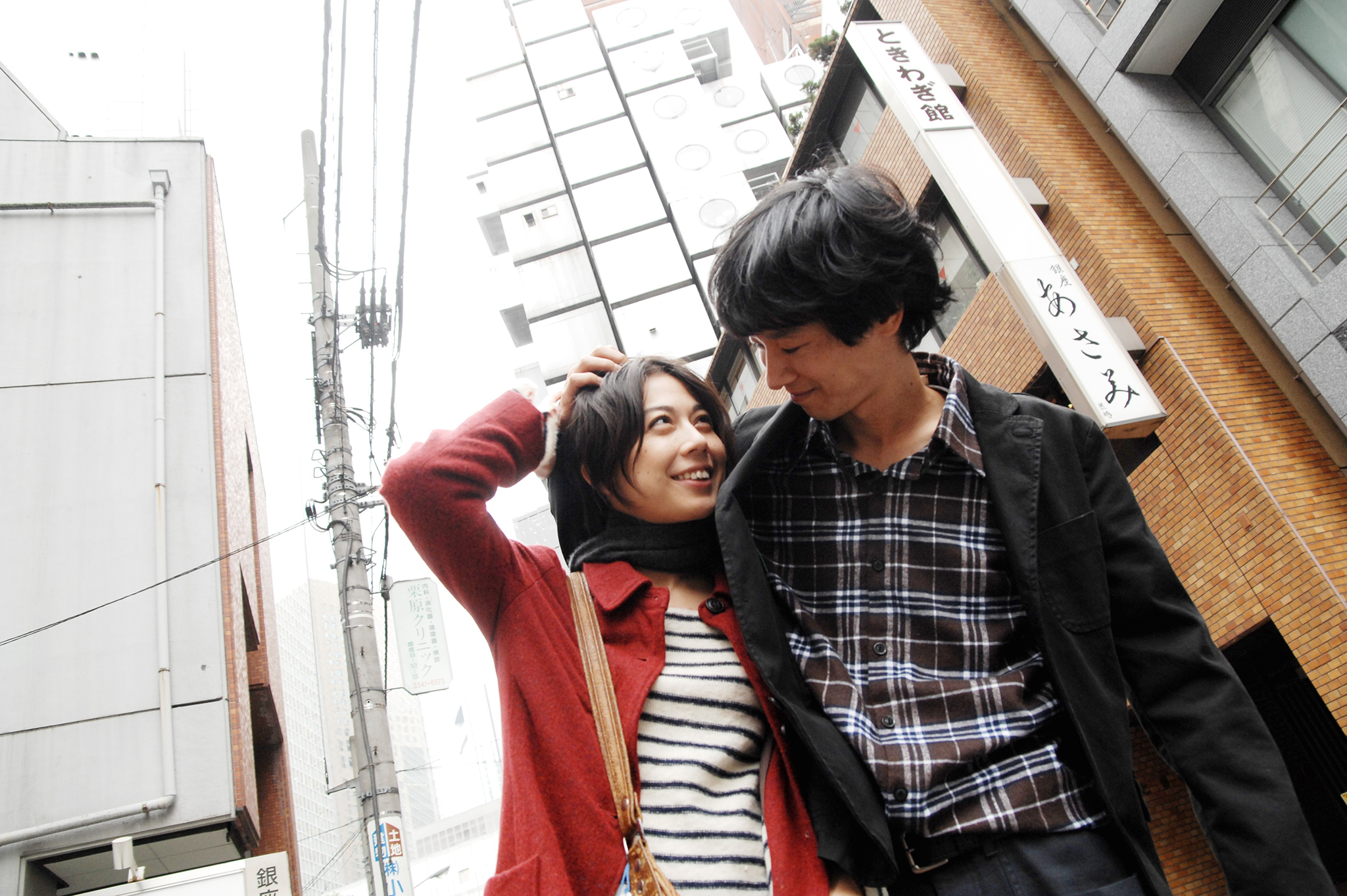 Hiroko (Ayako Fujitani) und Akira (Ryo Kase) halten sich bei einem Spaziergang durch Tokio gegenseitig im Arm und lächeln sich an.