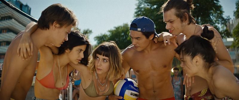 Sechs braungebrannte Jugendliche halten bei einer Pause im Beach Football Kriegsrat - Neu auf Netflix im Juli 2020