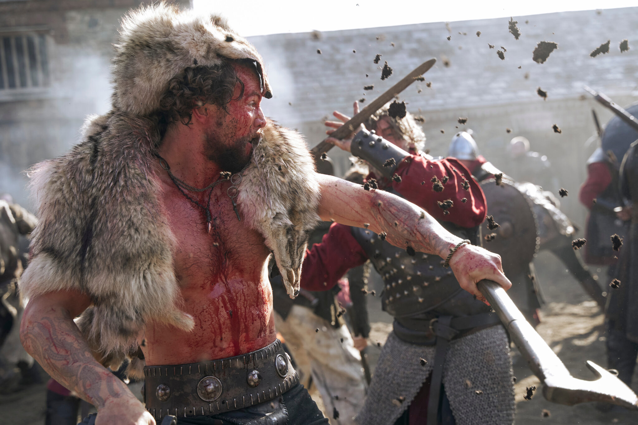 Ein Kampf zwischen einem Wikinger mit freiem Oberkörper, blutverschmiert, und Fell über dem Kopf und einem Angreifer mit erhobenem Schwert.