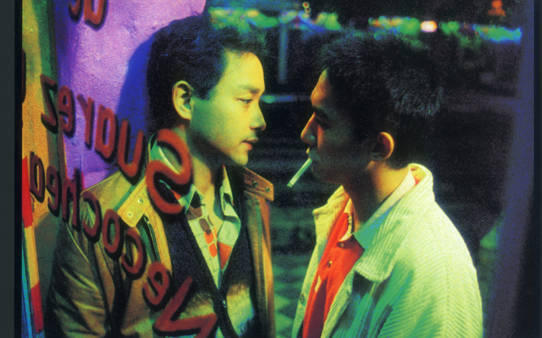 Ho Po-wing und Lai Yiu-fai eng zusammen hinter einer Glasfassade. Lai hat eine Zigarette zwischen den Lippen. 