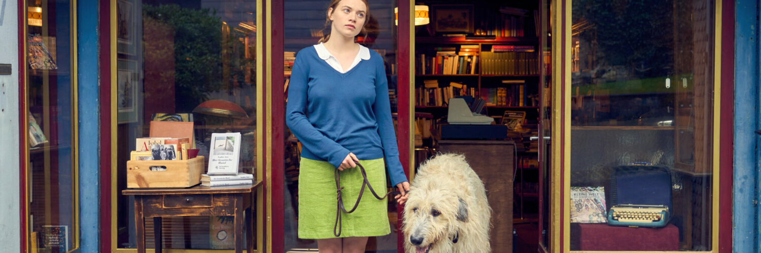 Luise (Luna Wedler) und Hund Alaska stehen vor der Buchhandlung