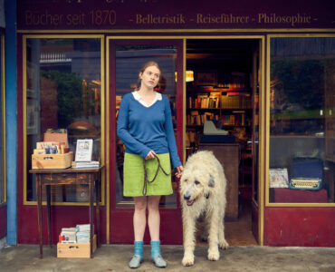 Luise (Luna Wedler) und Hund Alaska stehen vor der Buchhandlung