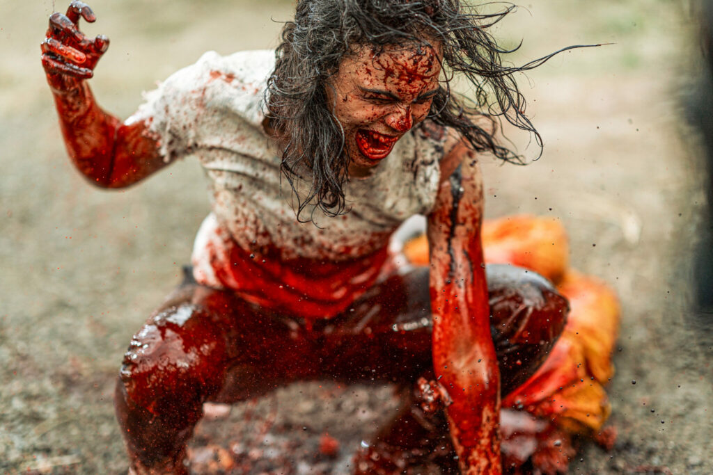 In Wyrmwood: Apocalypse schlägt die zombiefizierte Grace, gespielt von Tasia Zalar, auf ihr am Boden liegendes Opfer ein und zerfleischt es blutrünstig.